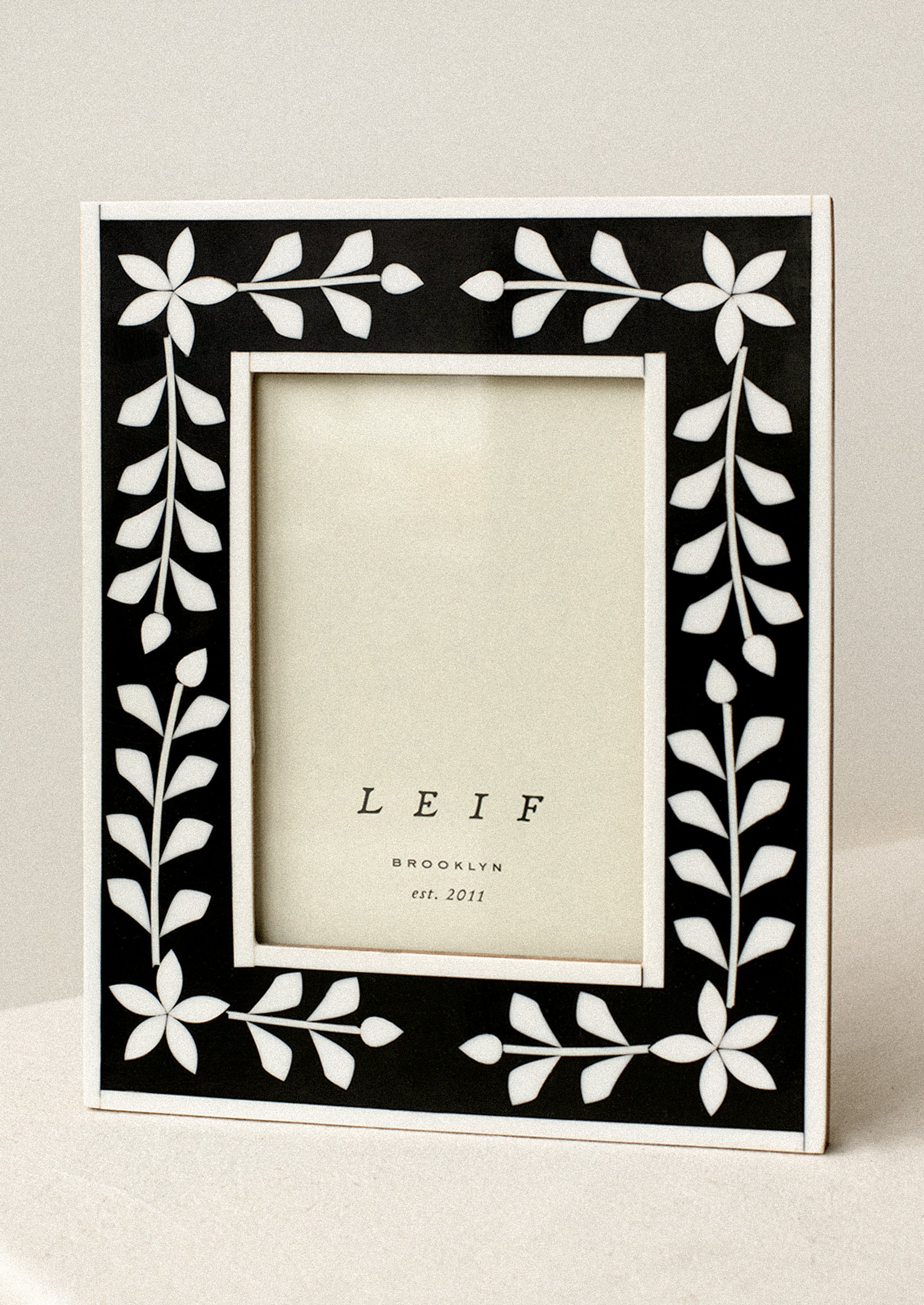 A black and white inlay frame with flower pattern.