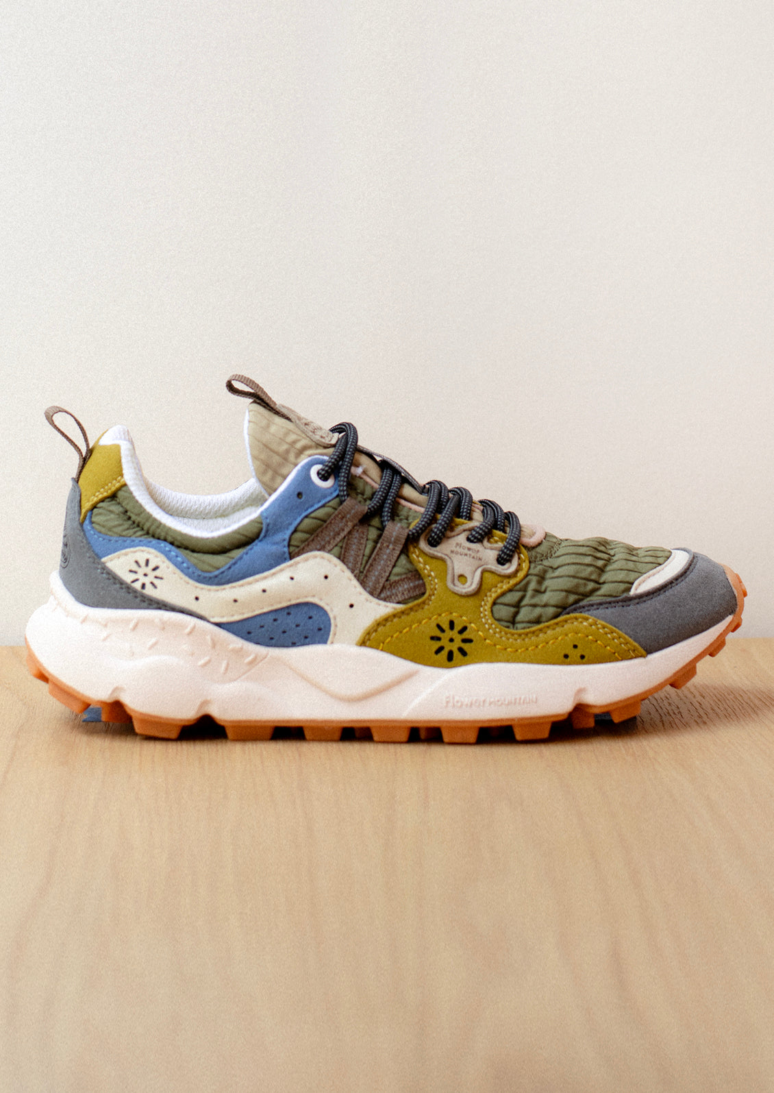 A pair of sneakers in ribbed nylon and suede, green and mustard color palette.