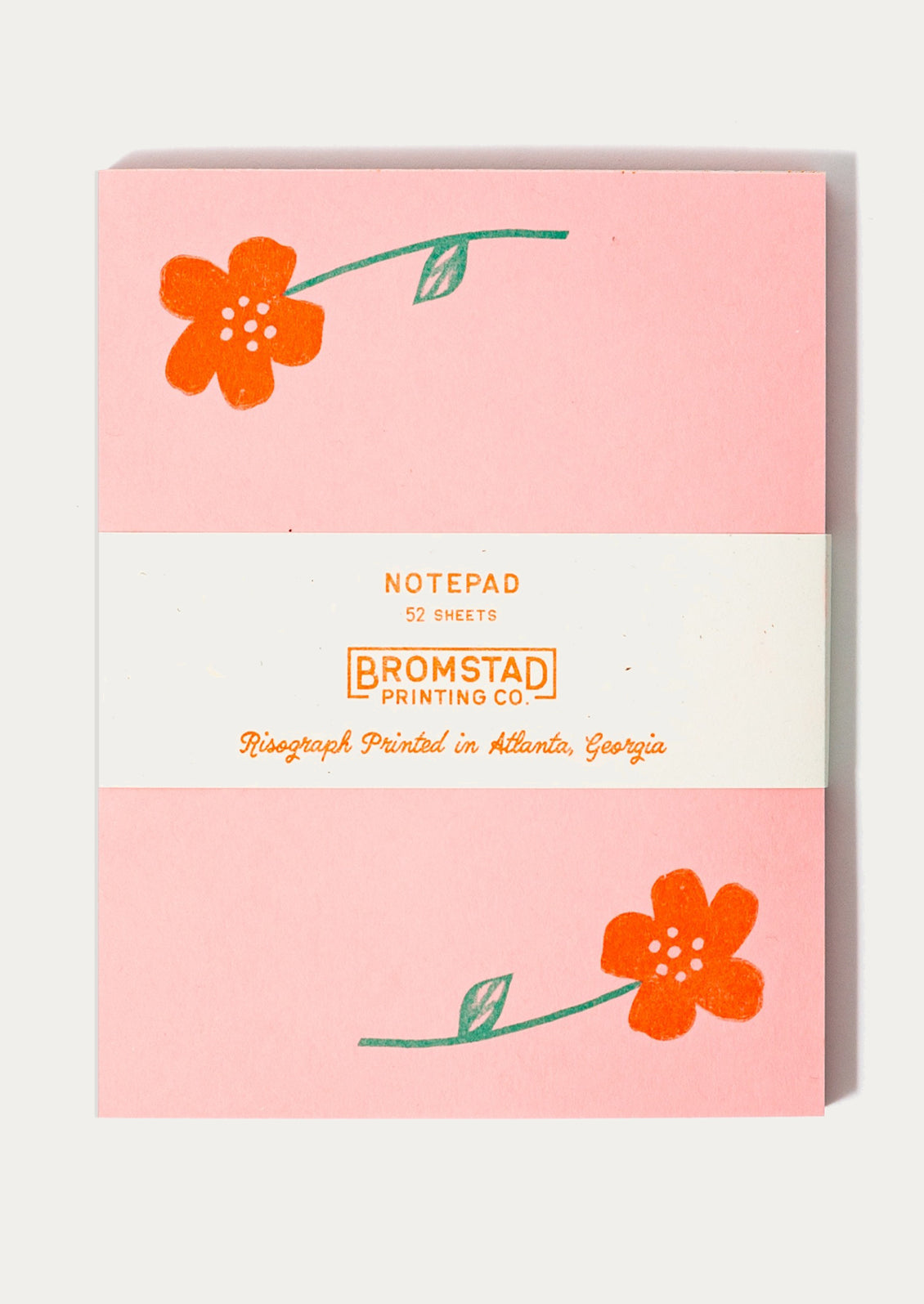 A pink notepad with neon orange flower print at corners.