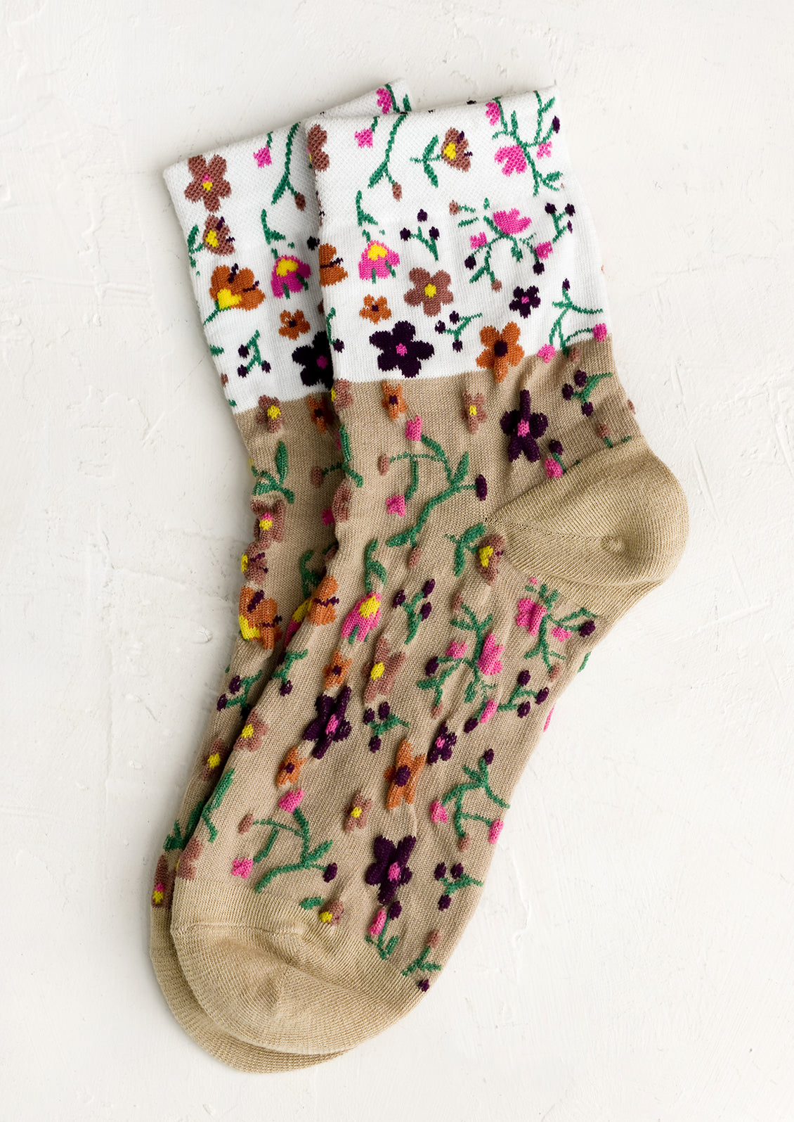 A pair of two-tone socks in white and tan with multicolor flower pattern.
