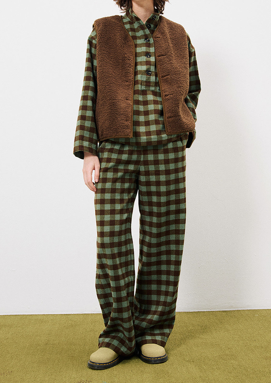 A person wearing a pair of pants in green and brown gingham pattern.