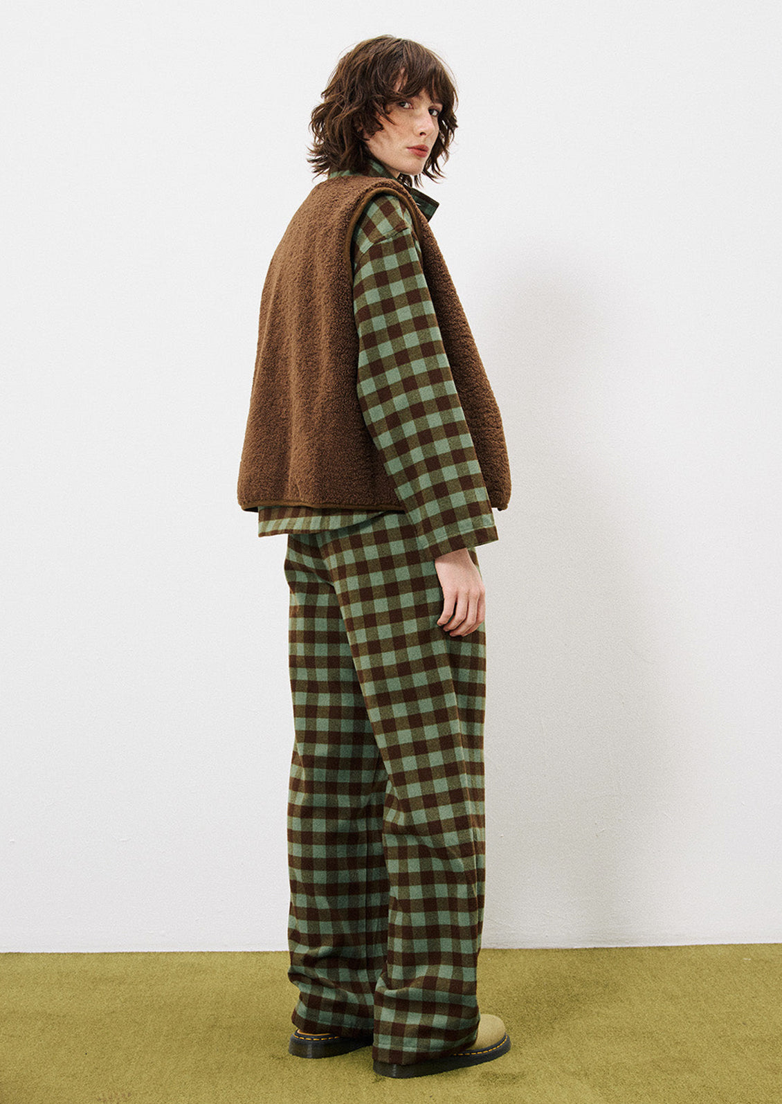 A person wearing a pair of pants in green and brown gingham pattern.