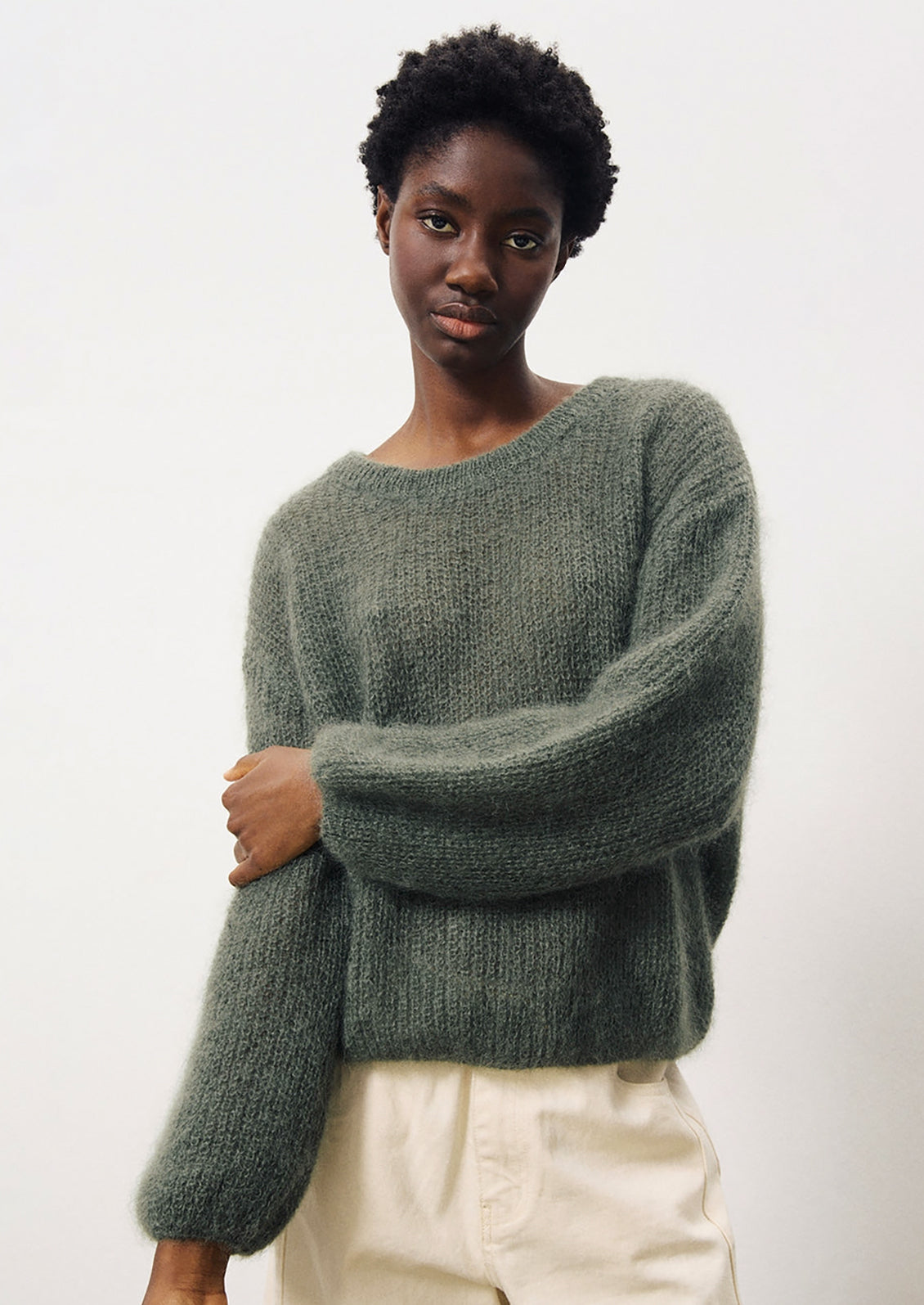 A woman wearing a mohair sweater in dusty khaki grey-green color.