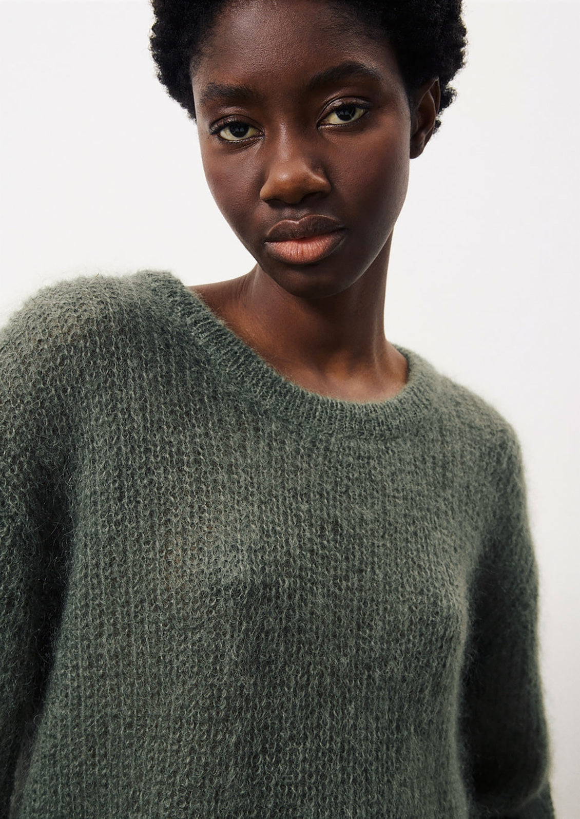 A woman wearing a mohair sweater in dusty khaki grey-green color.