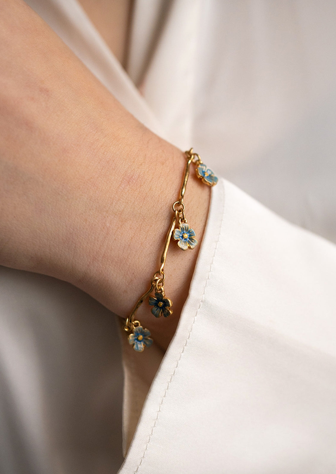 A gold bracelet with blue flower charms.