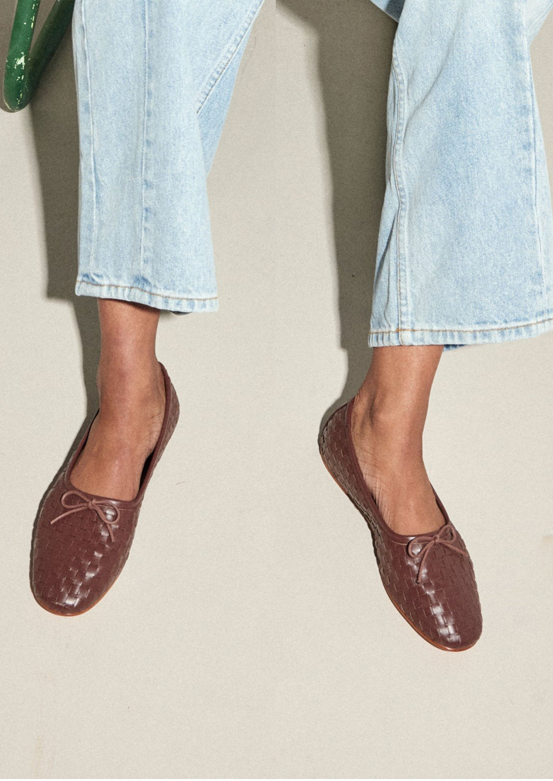 A woman wearing dark brown leather ballet flats.