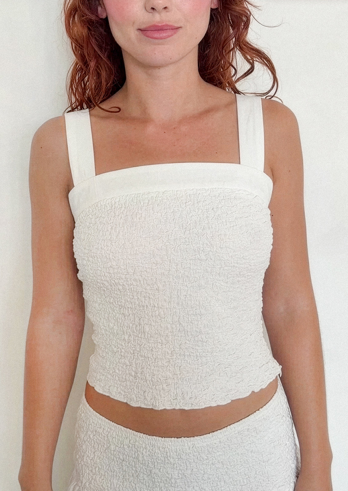 Woman wearing a white textured top against a plain background