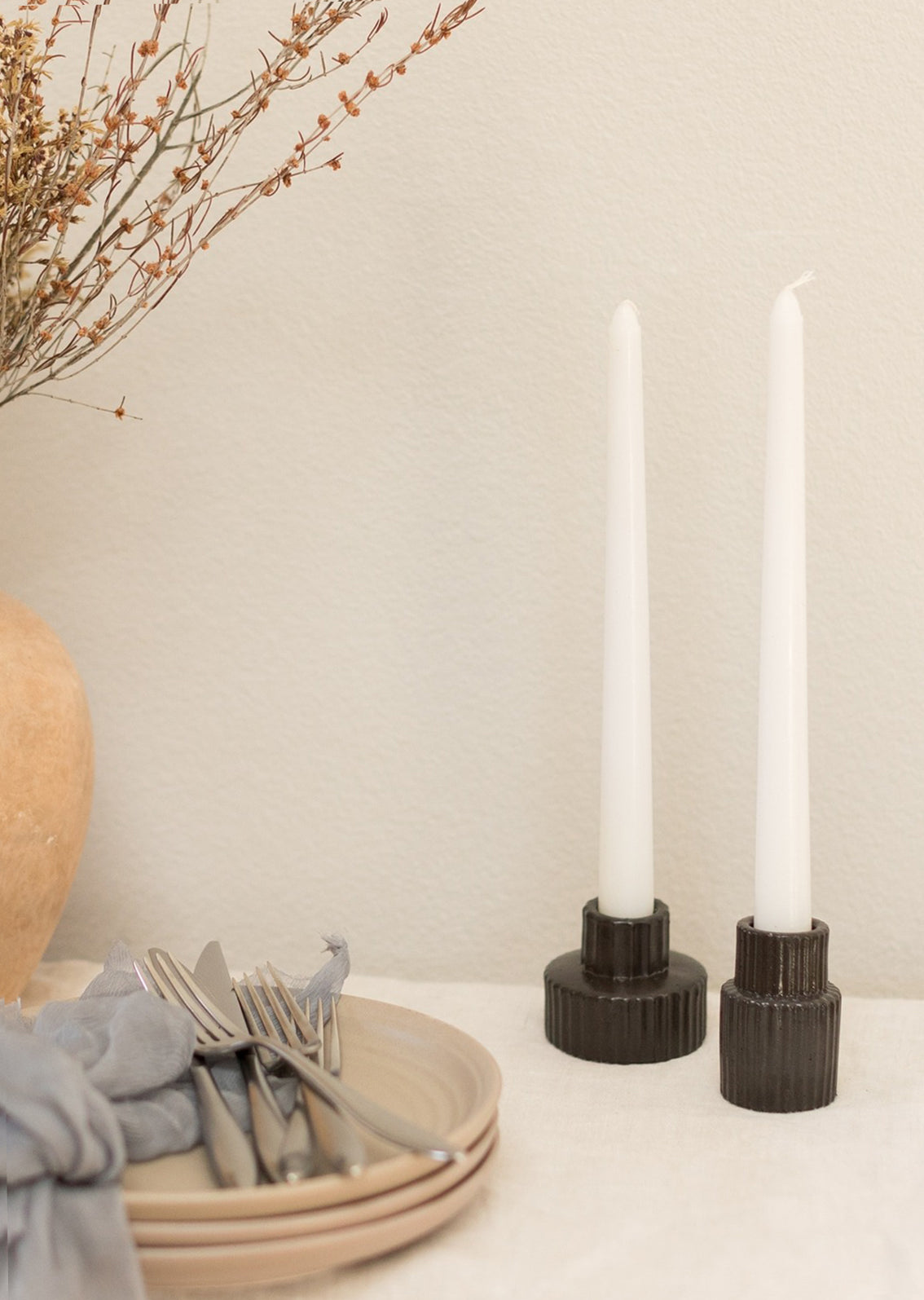 Black fluted taper candle holders on table scene.