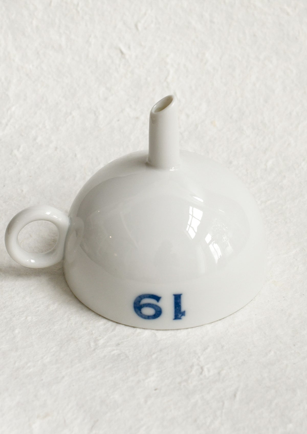 A ceramic funnel in white with printed blue text.