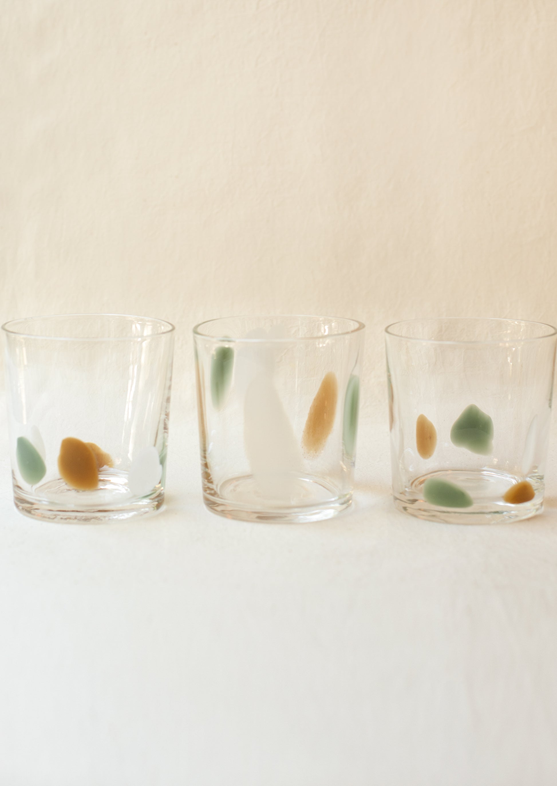 A stack of clear glass tumblers with mint, brown and white speckle pattern.