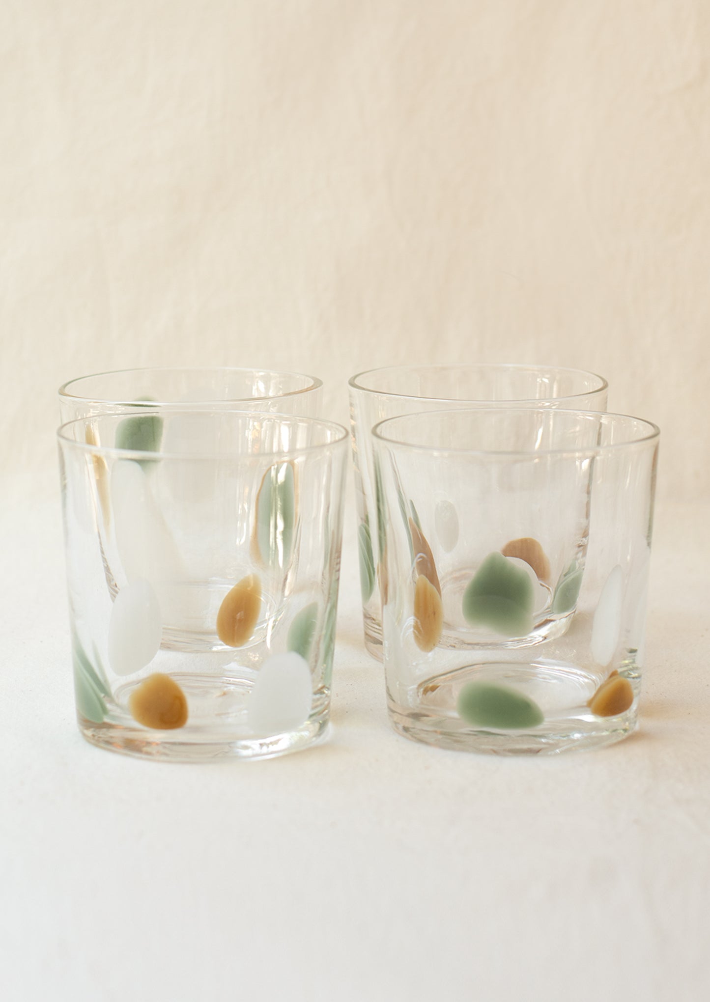 A stack of clear glass tumblers with mint, brown and white speckle pattern.