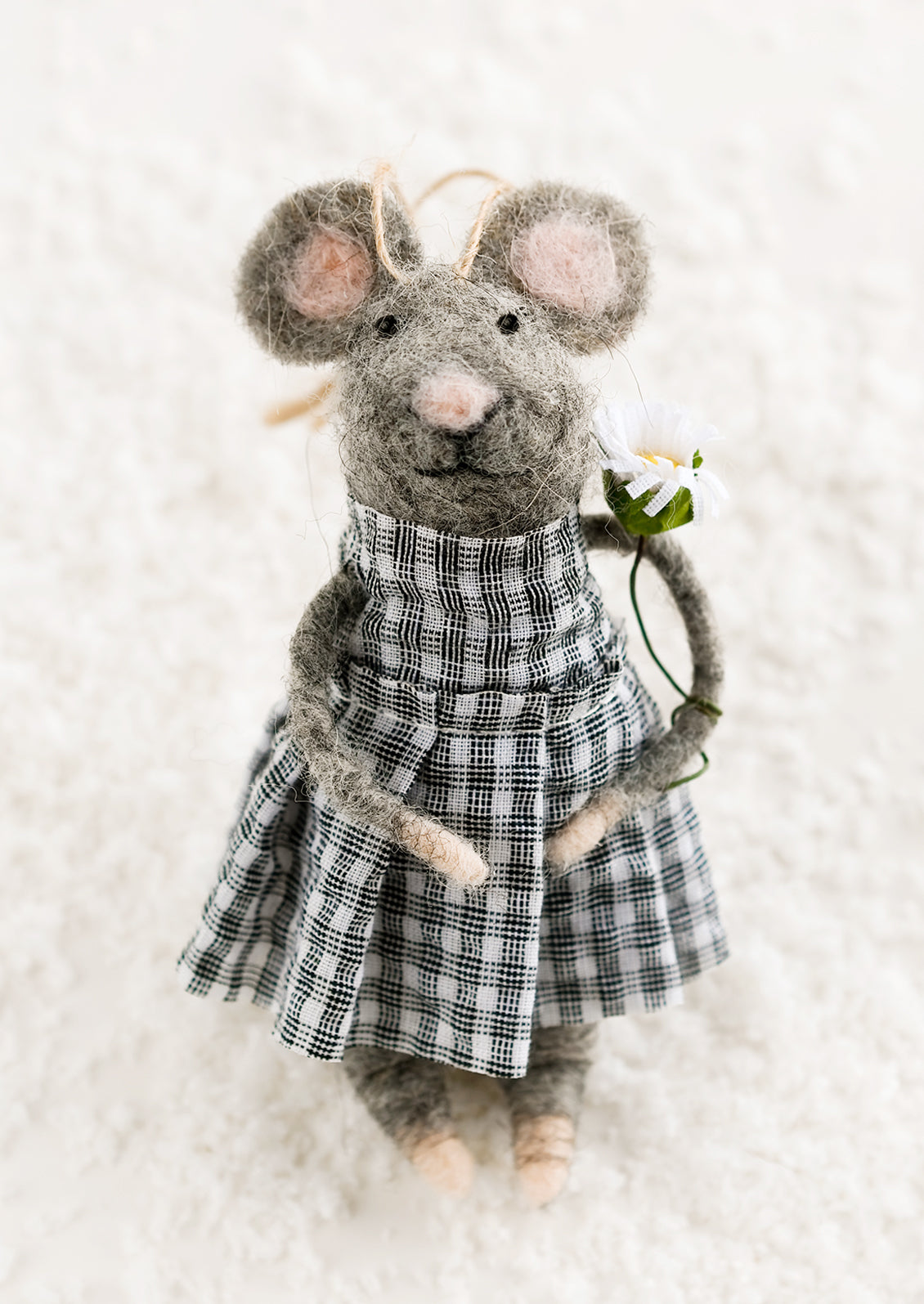 A felted grey mouse ornament in gingham dress, holding flower.