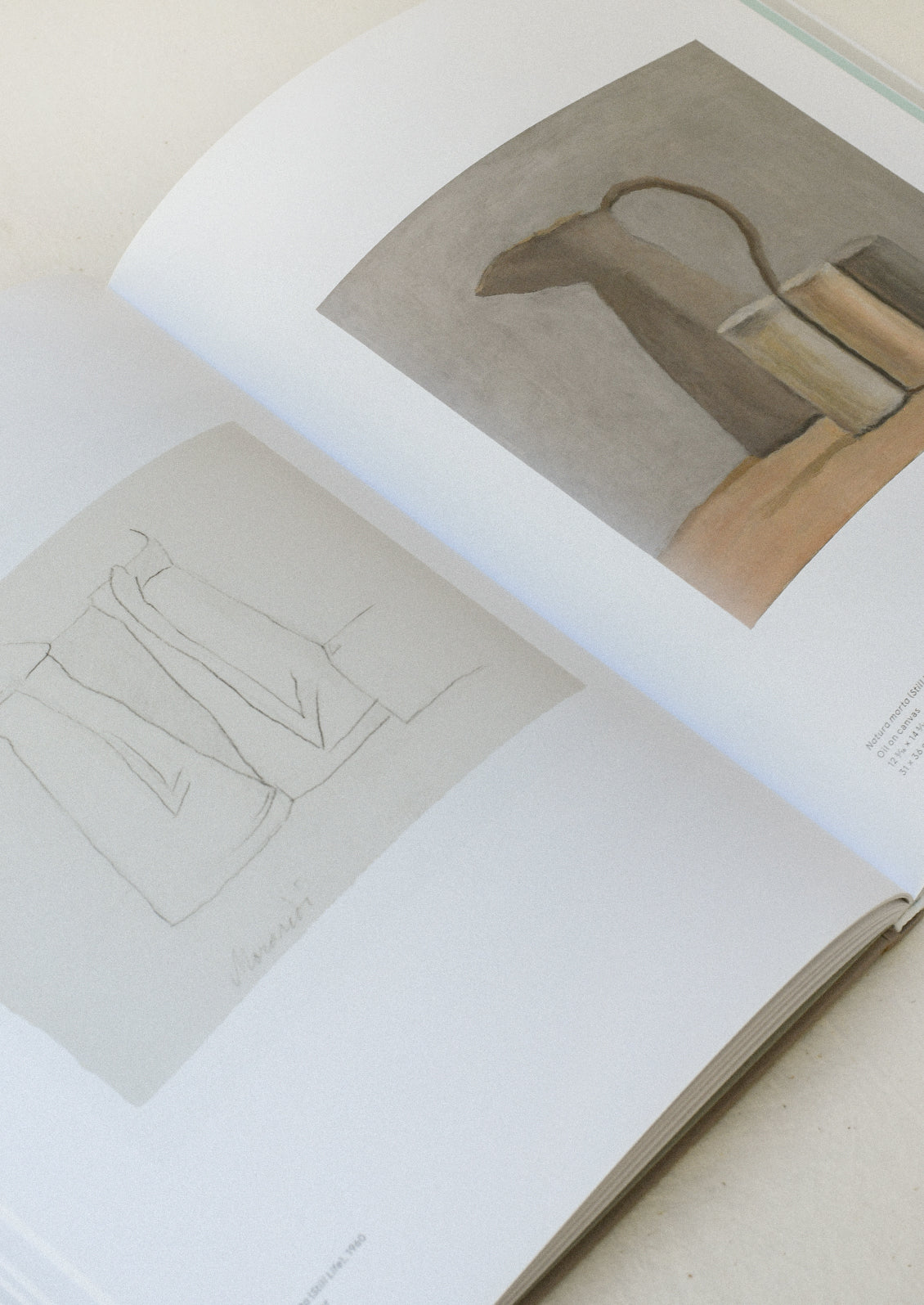 An open book sitting on a table showing two pages, each with an illustration by Giorgio Morandi.