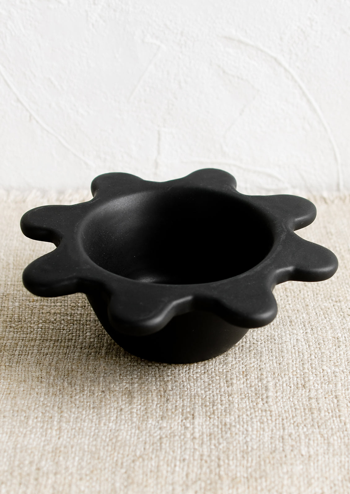 A small black ceramic bowl with splatter squiggle shape rim.