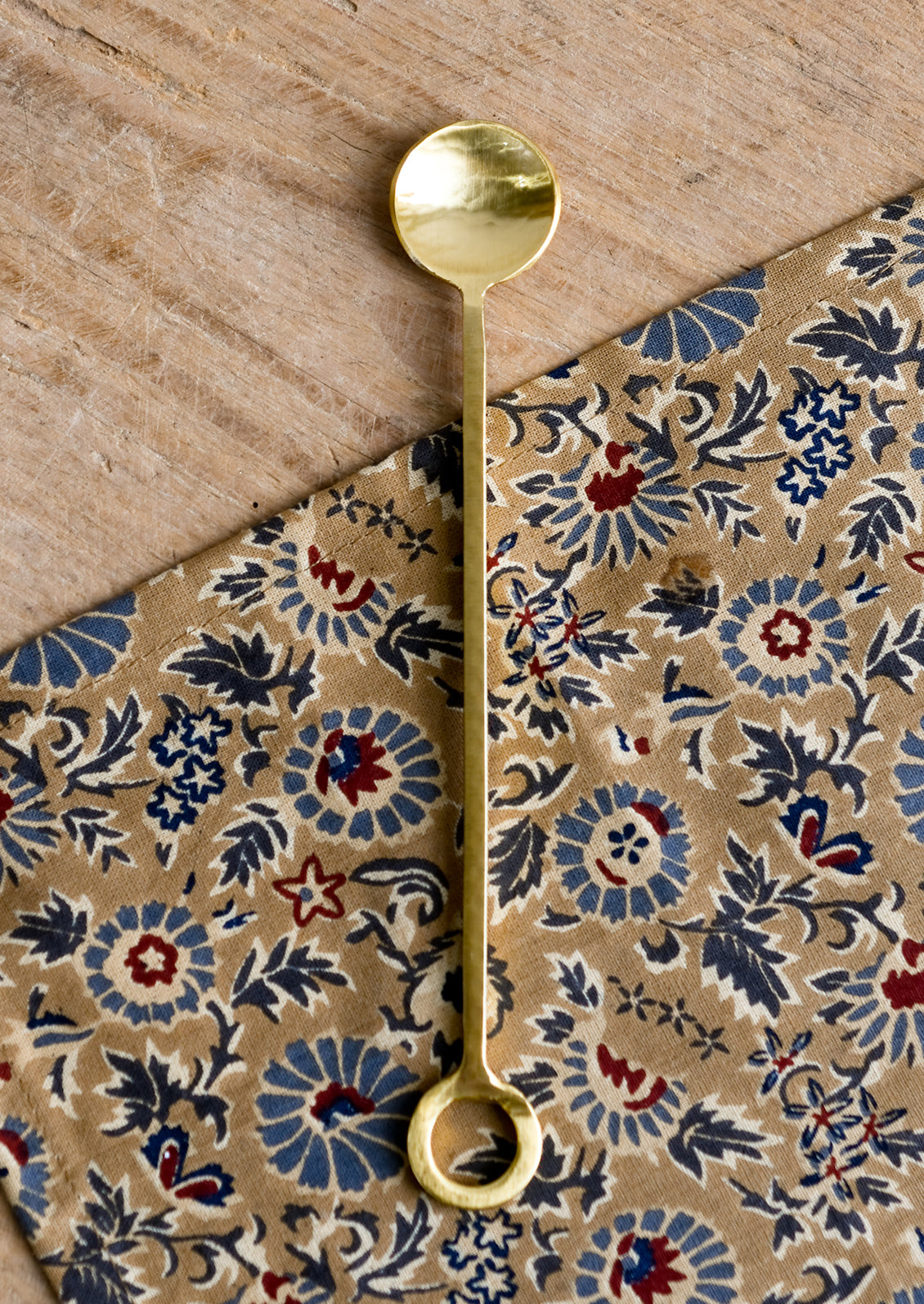 Gold finish cocktail spoon with circular loop at end of handle.