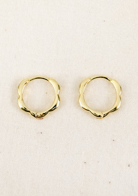 A pair of small gold hoop earrings with a scallop edge design