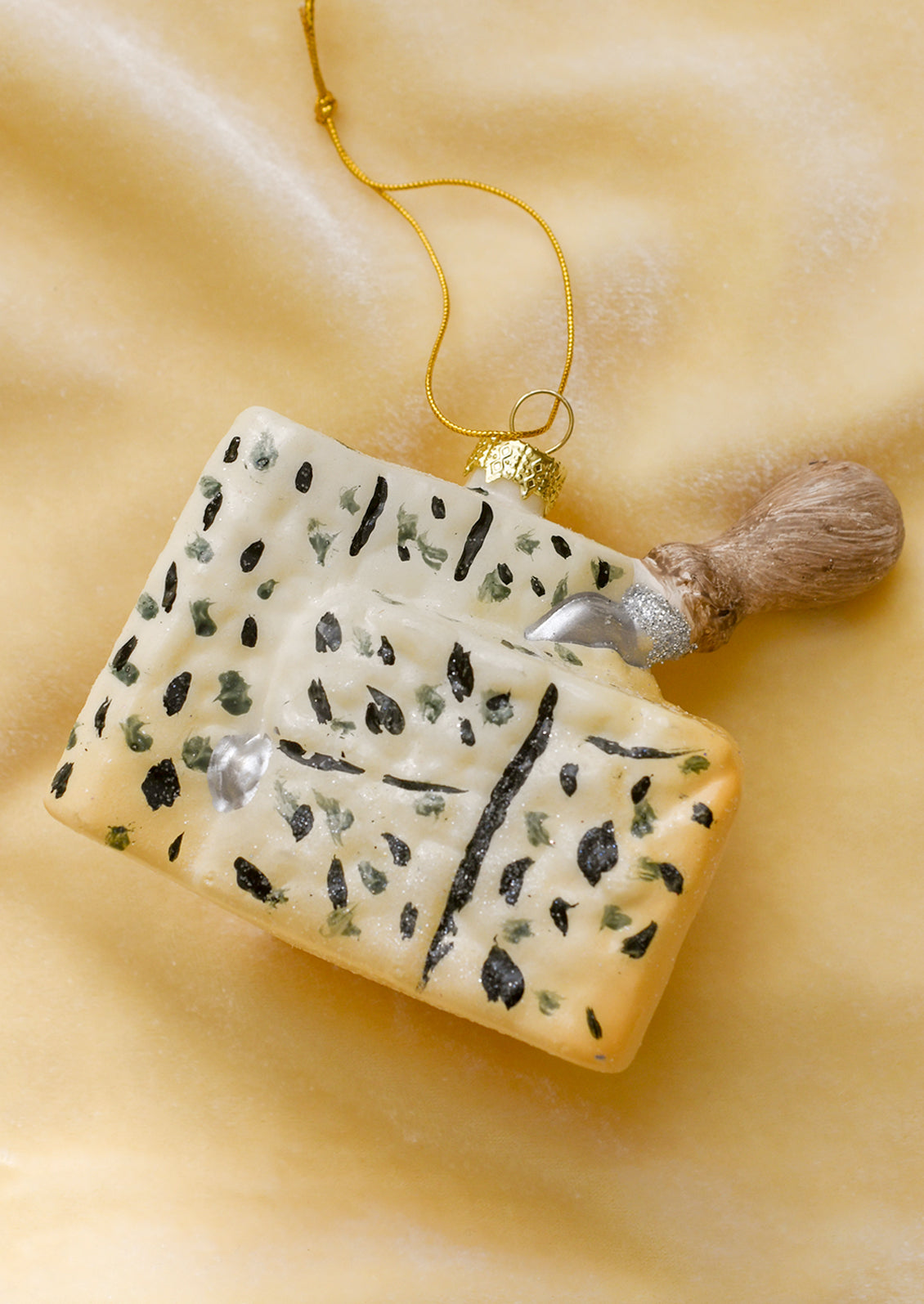 A glass ornament of a wedge of gorgonzola with cheese knife sticking out.
