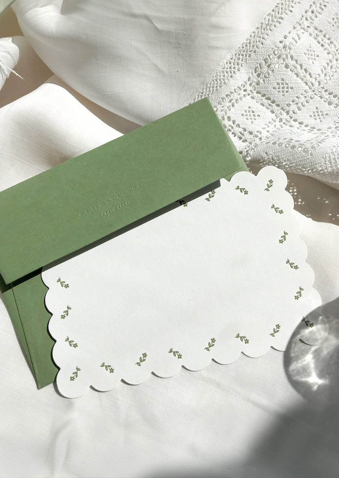 A scalloped white notecard with green floral border and green envelope.