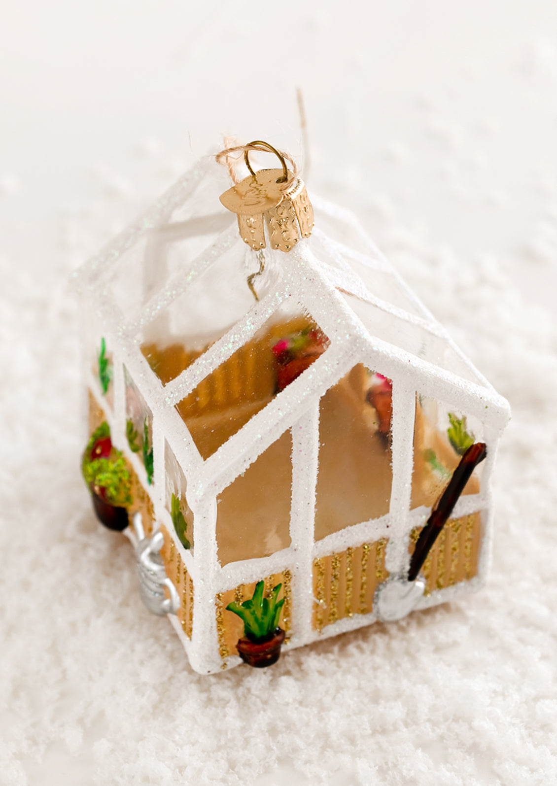 A decorative glass holiday ornament of a glass greenhouse.