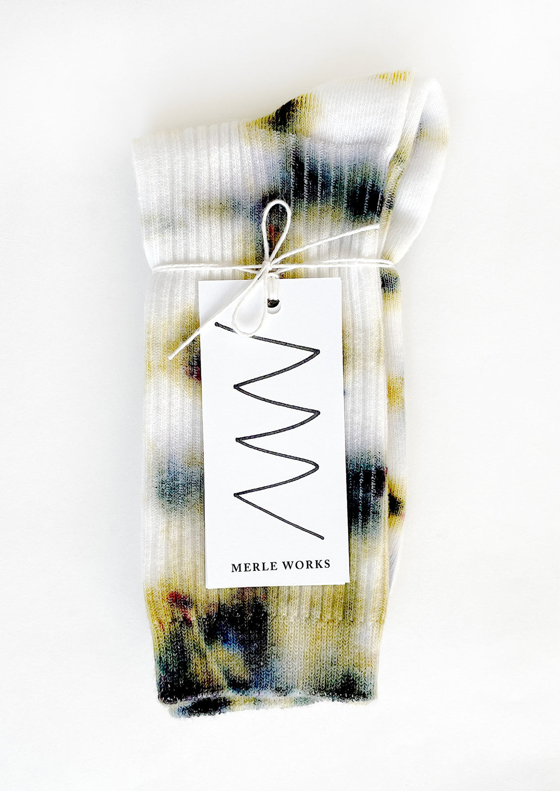 A pair of tie dye socks in white with mossy green and blue.