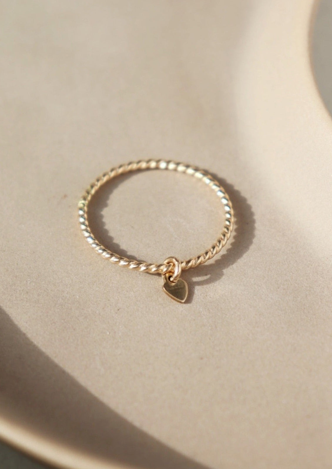 A gold ring with a tiny heart charm.
