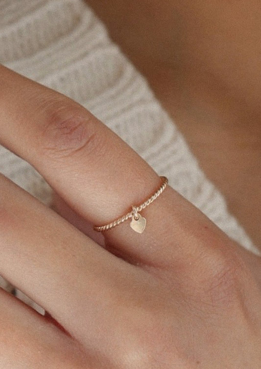 A gold ring with a tiny heart charm.