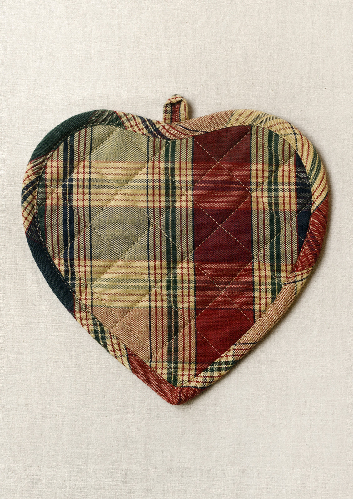 A heart shaped pot holder in multicolor plaid pattern.
