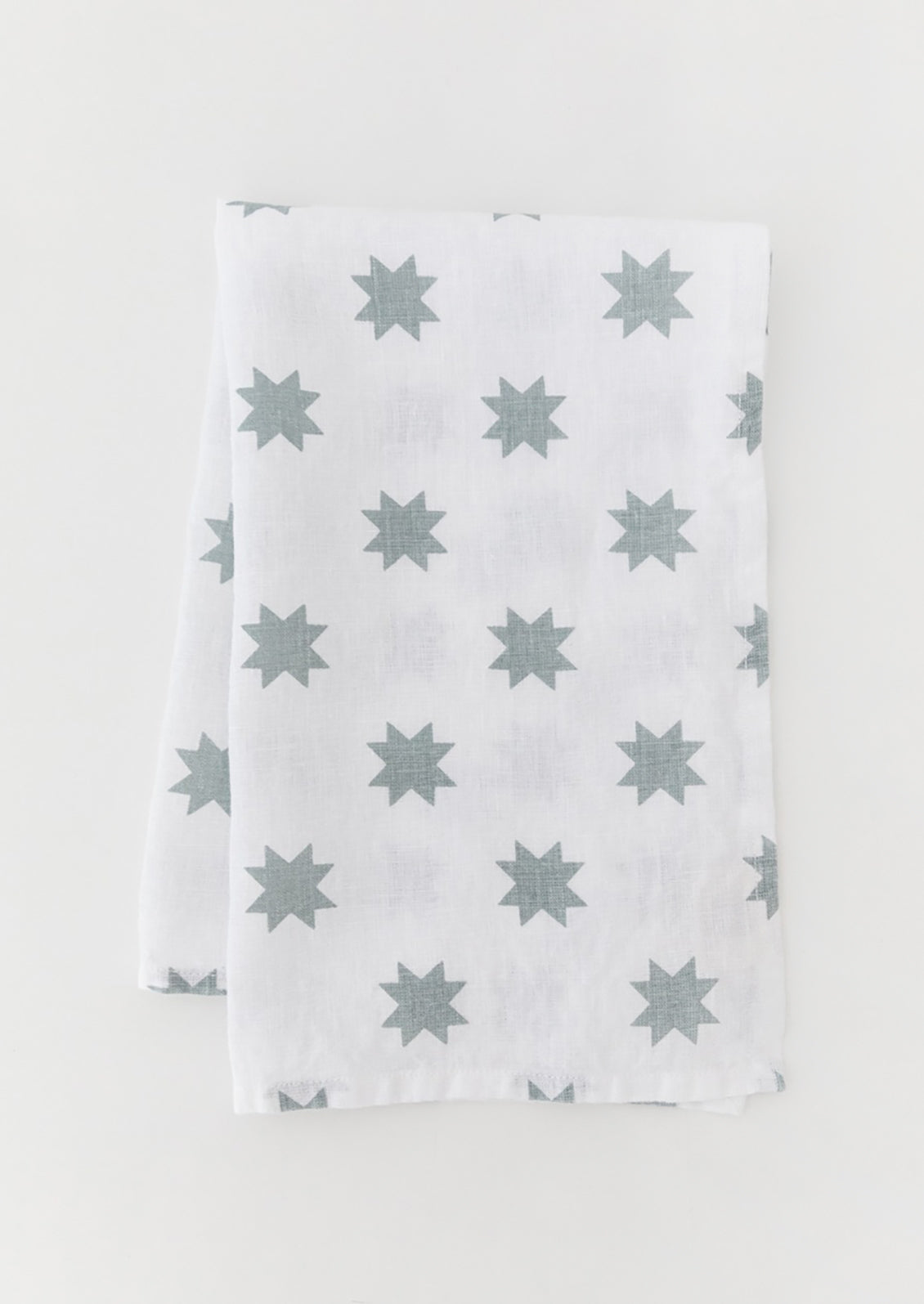 A white linen tea towel with dusty blue star pattern.