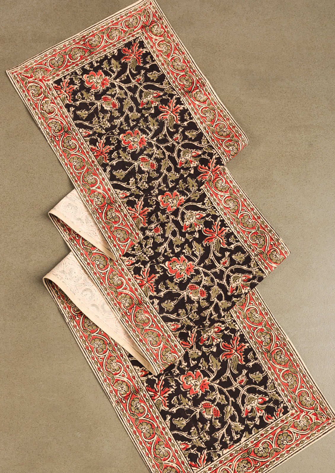 A table runner with black and red floral print.