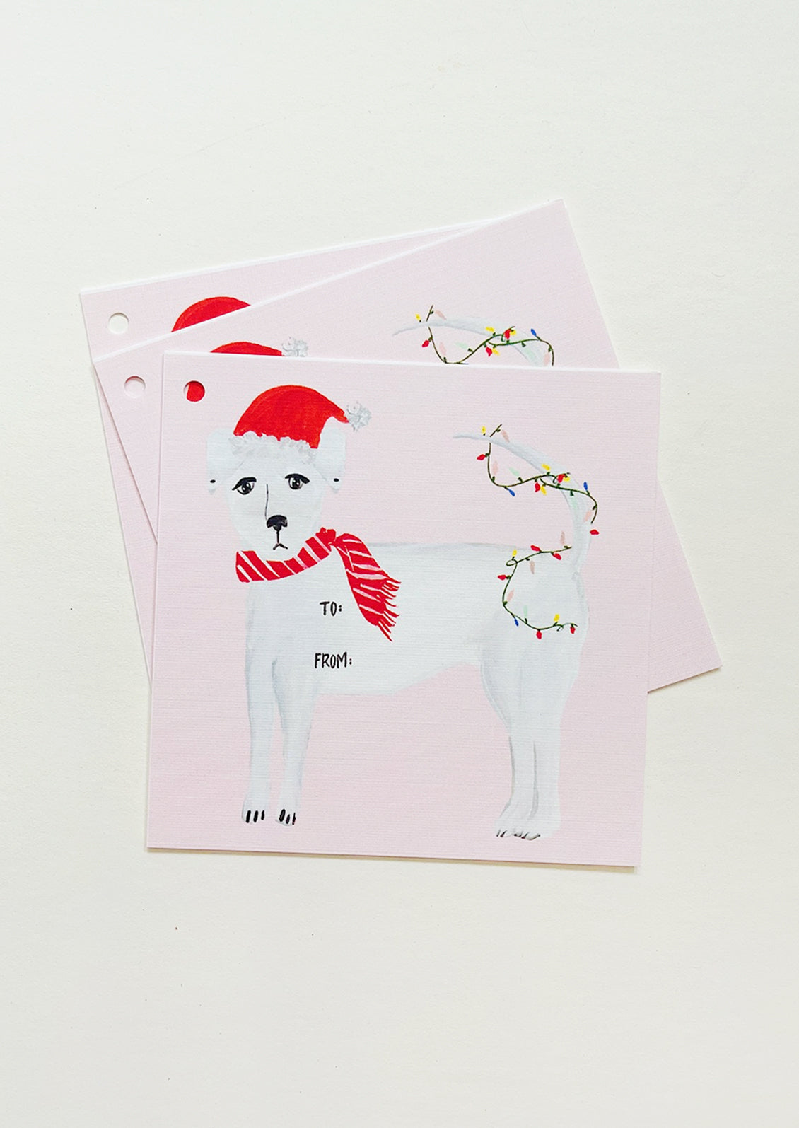 Pink square gift tags with image of white dog wearing Santa hat and tree lights.