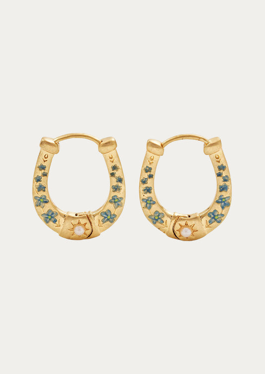A pair of hold horseshoe shaped gold earrings with blue flowers.