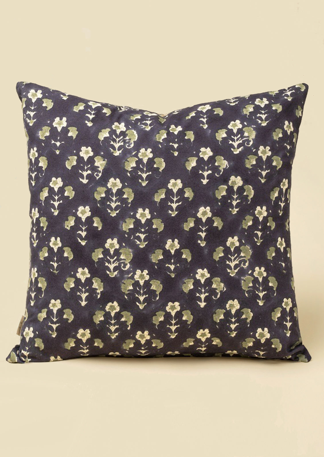 A block printed throw pillow with dark blue background and sage green floral print.