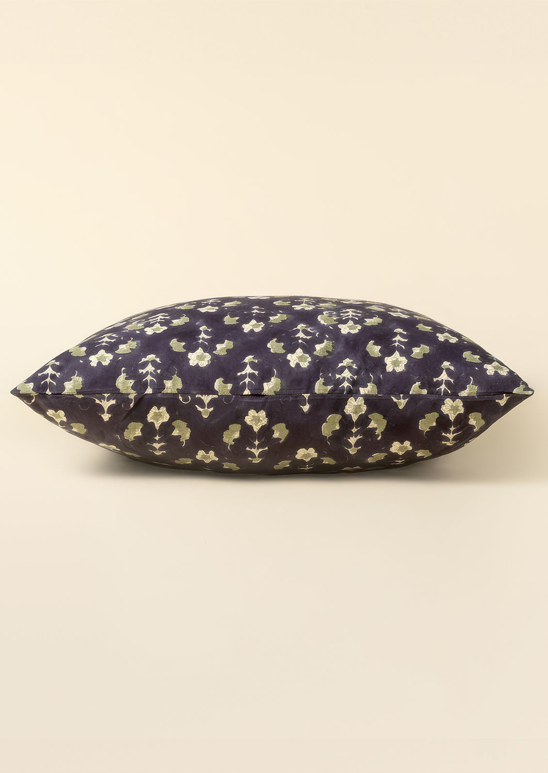 A block printed throw pillow with dark blue background and sage green floral print.