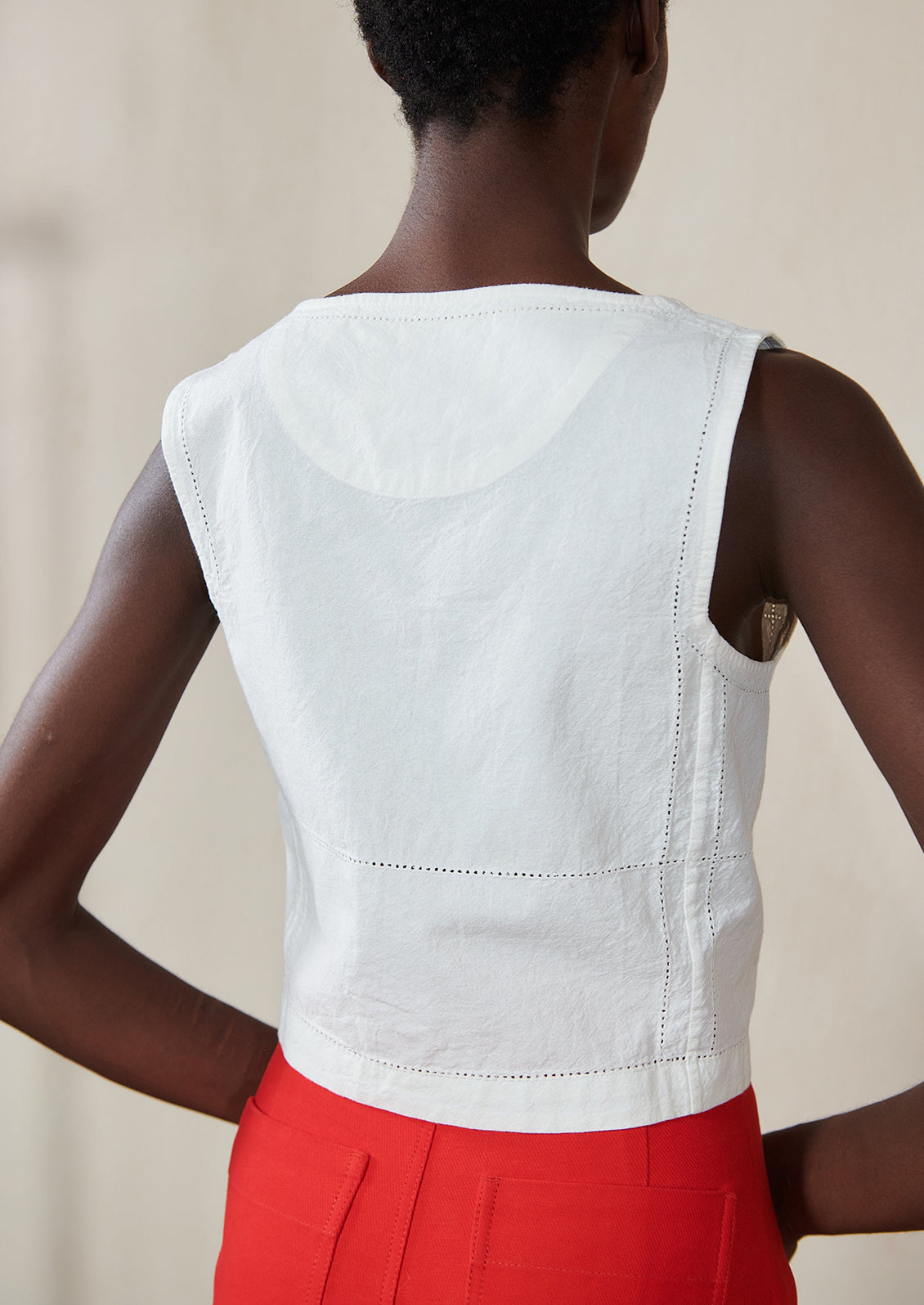 A woman wearing a white square neck tank.