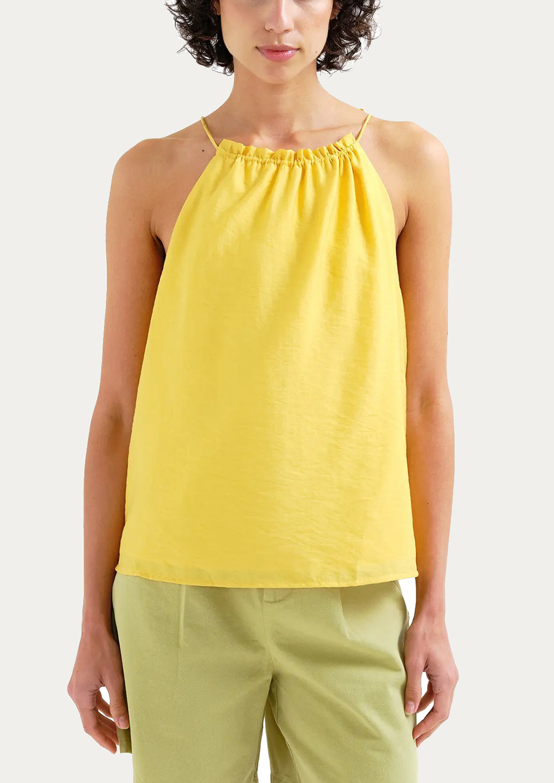 Woman wearing a yellow sleeveless top on a white background