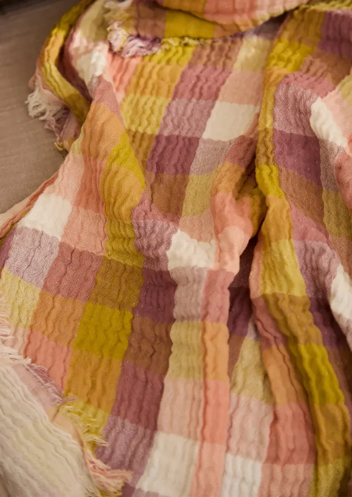 Close-up of a checkered blanket with pink, yellow, and white colors.