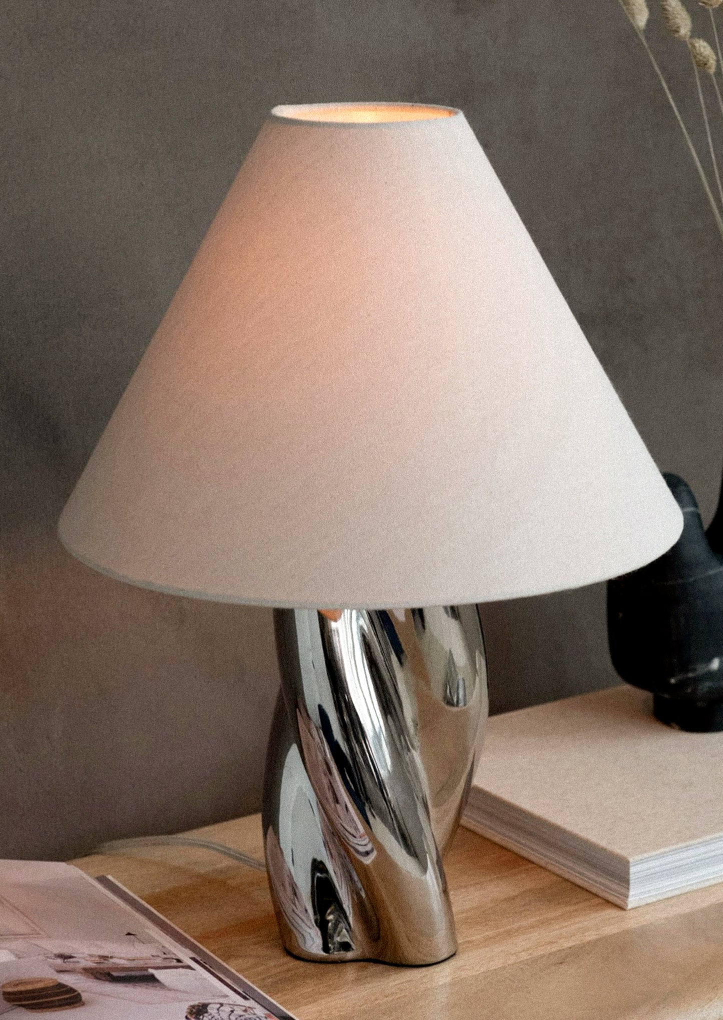 Table lamp with a twisted shape chrome base and white shade.