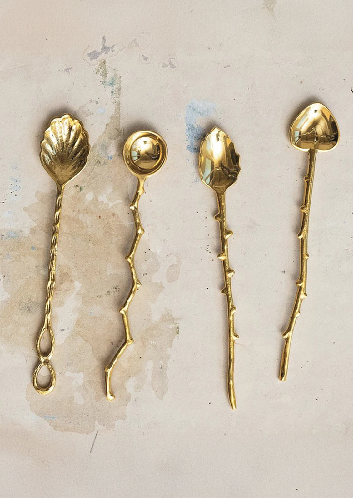 Assorted brass spoons in different shapes with twig-cast handles.