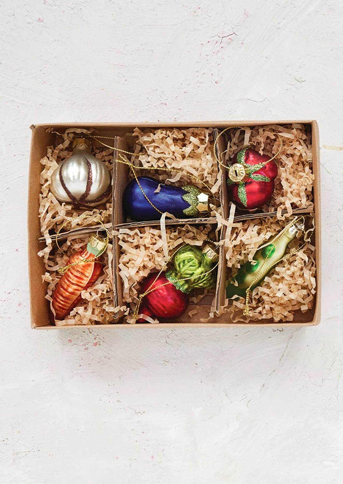 Set of colorful glass vegetable-shaped ornaments in a gift box with crinkle paper.