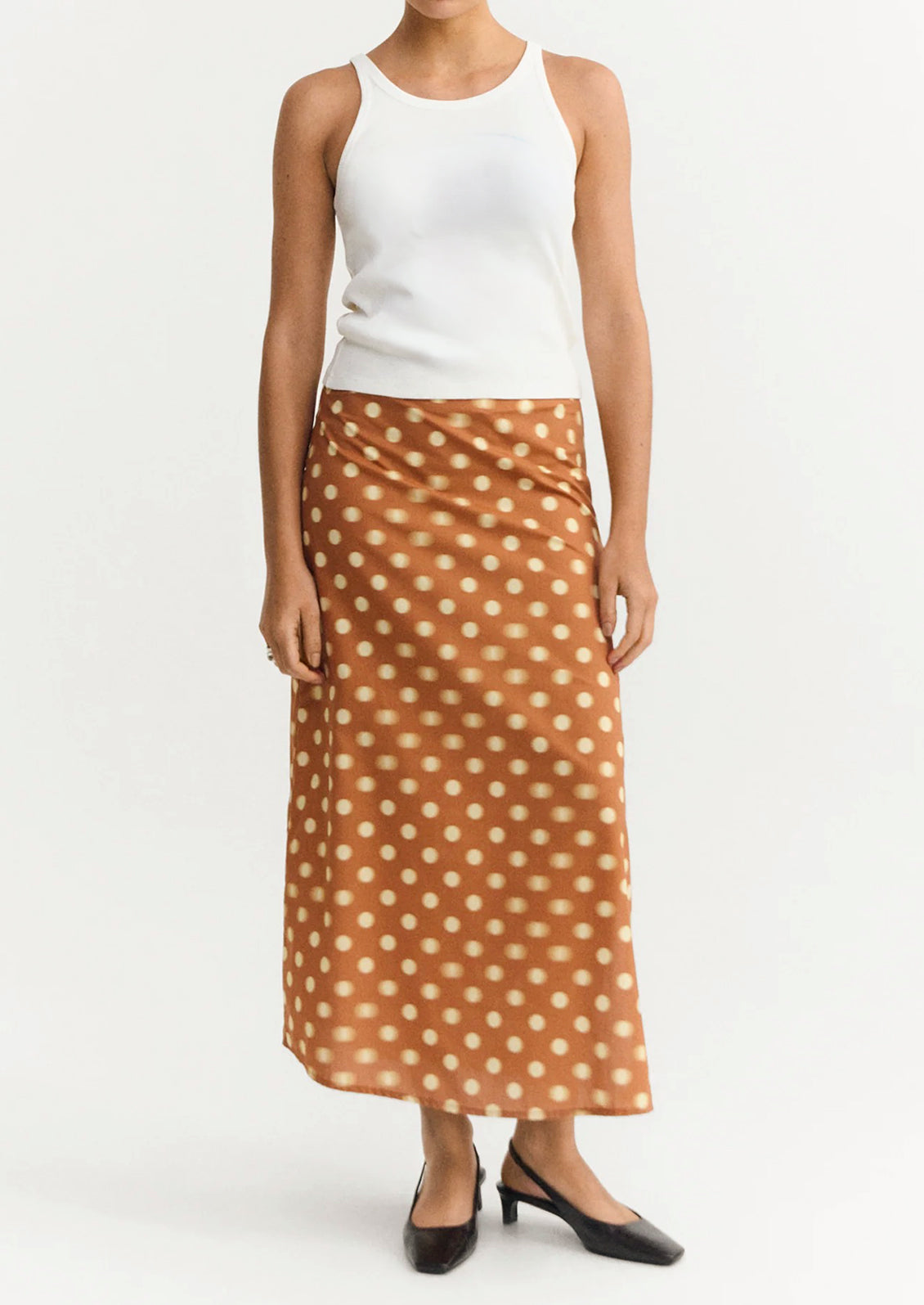 A woman wearing an ankle-length skirt in caramel with yellow polka dots.
