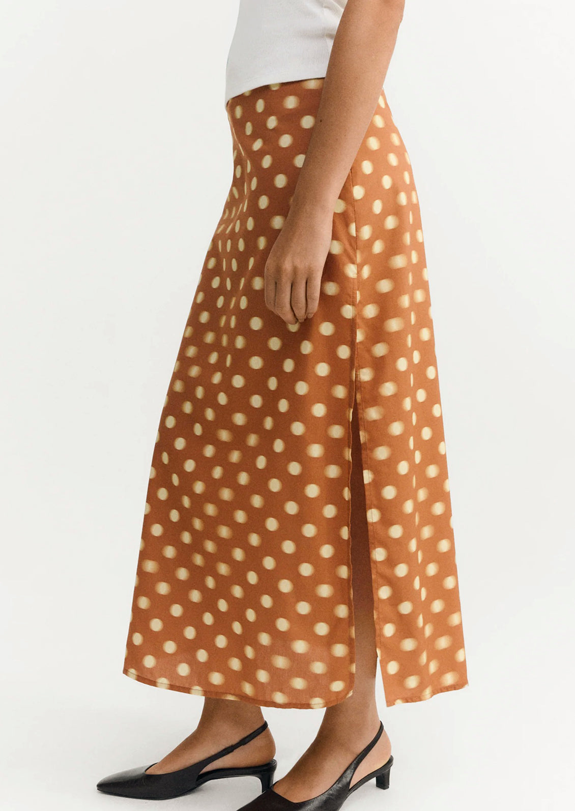 A woman wearing an ankle-length skirt in caramel with yellow polka dots.