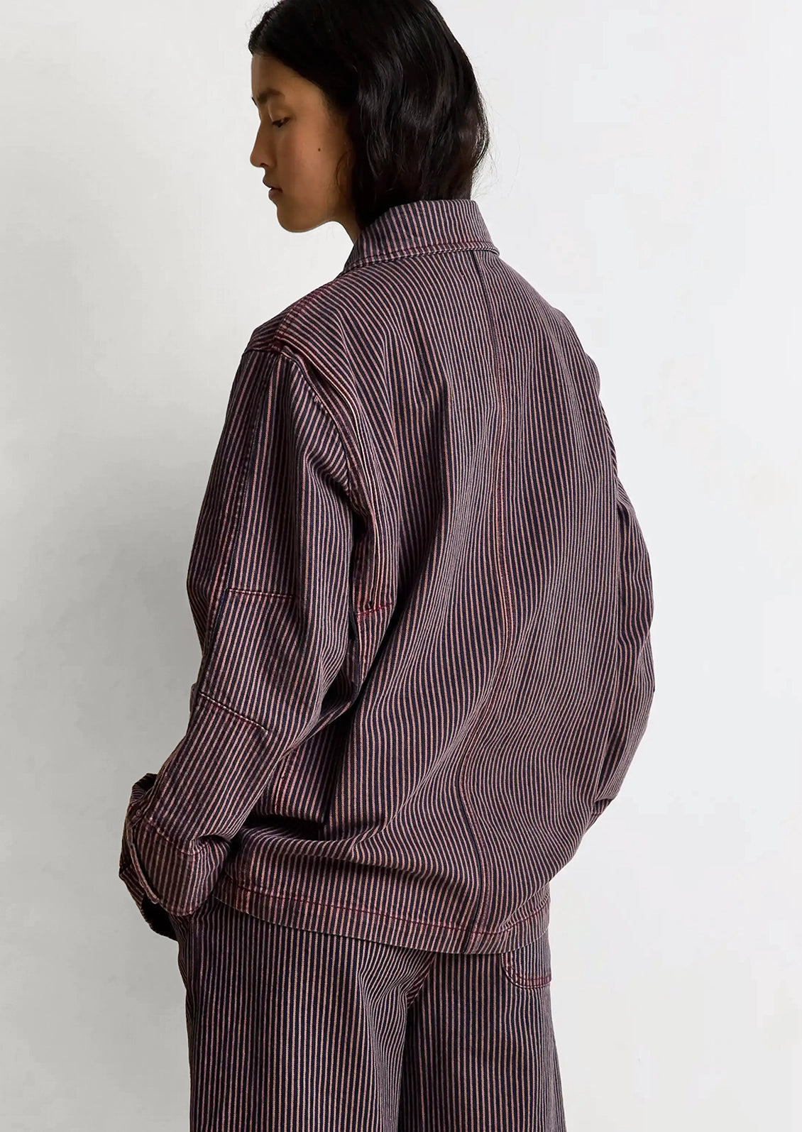 Person wearing a brown striped jacket and pants on a white background
