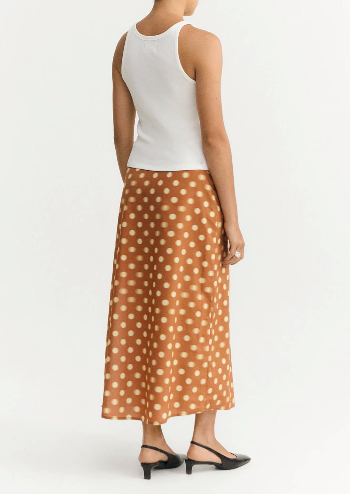 A woman wearing an ankle-length skirt in caramel with yellow polka dots.