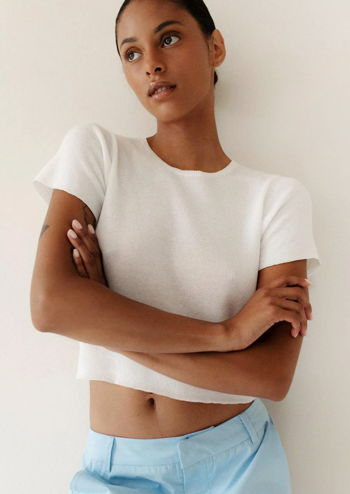 A person wearing a knit cropped t-shirt in white.