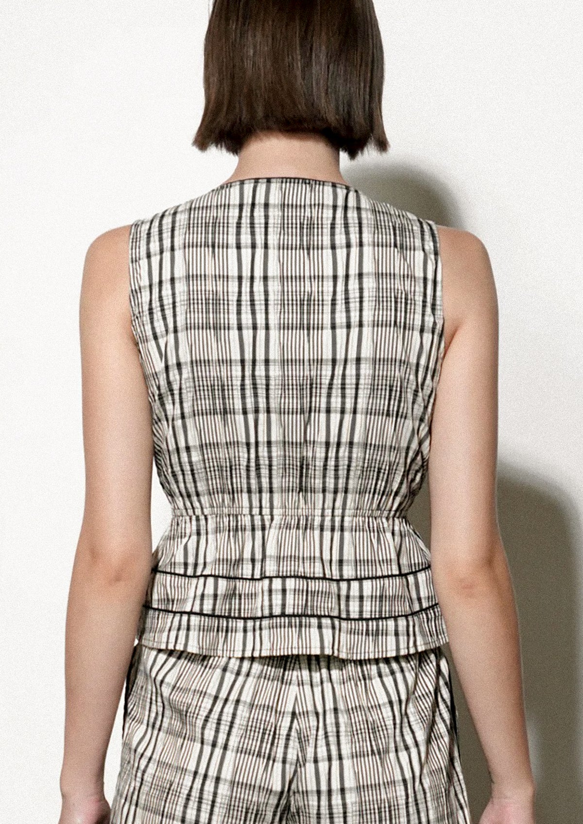 Woman wearing a black and white checkered top against a plain background