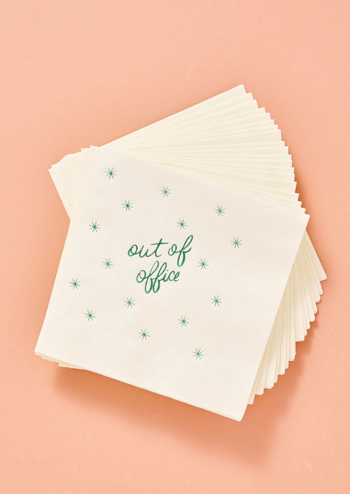 Stack of white paper napkins with 'out of office' text in green.