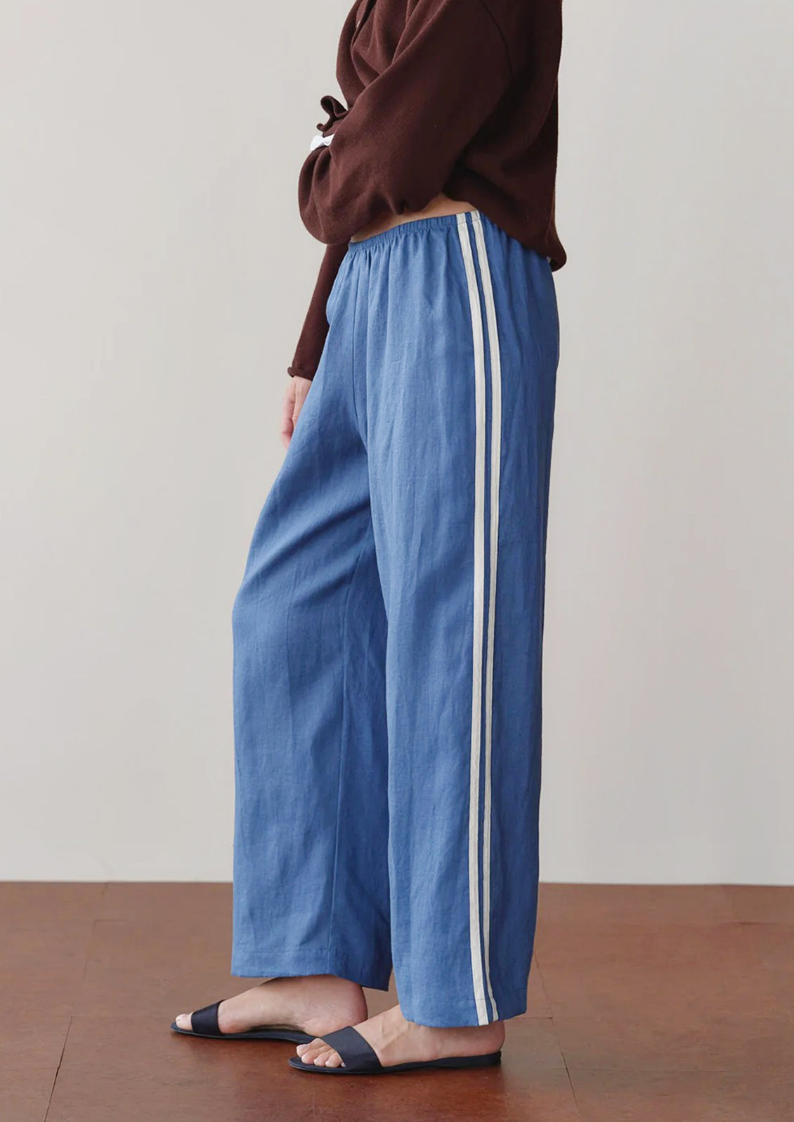 Blue pants with white stripes worn by a person on a plain background