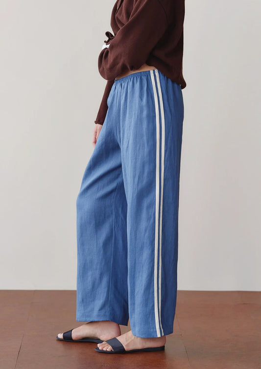 Blue pants with white stripes worn by a person on a plain background