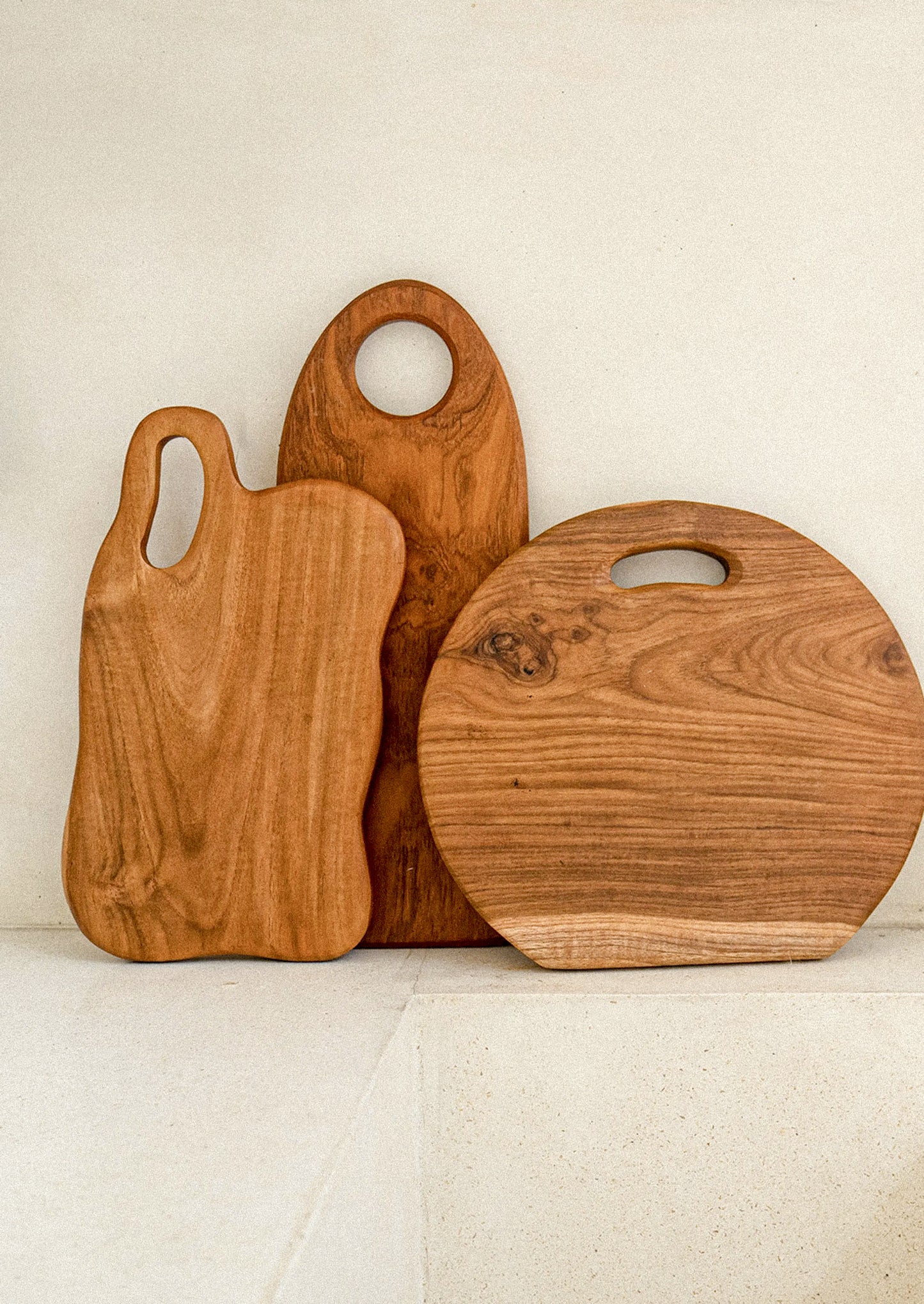Three wooden cutting boards of different shapes and sizes on a light background