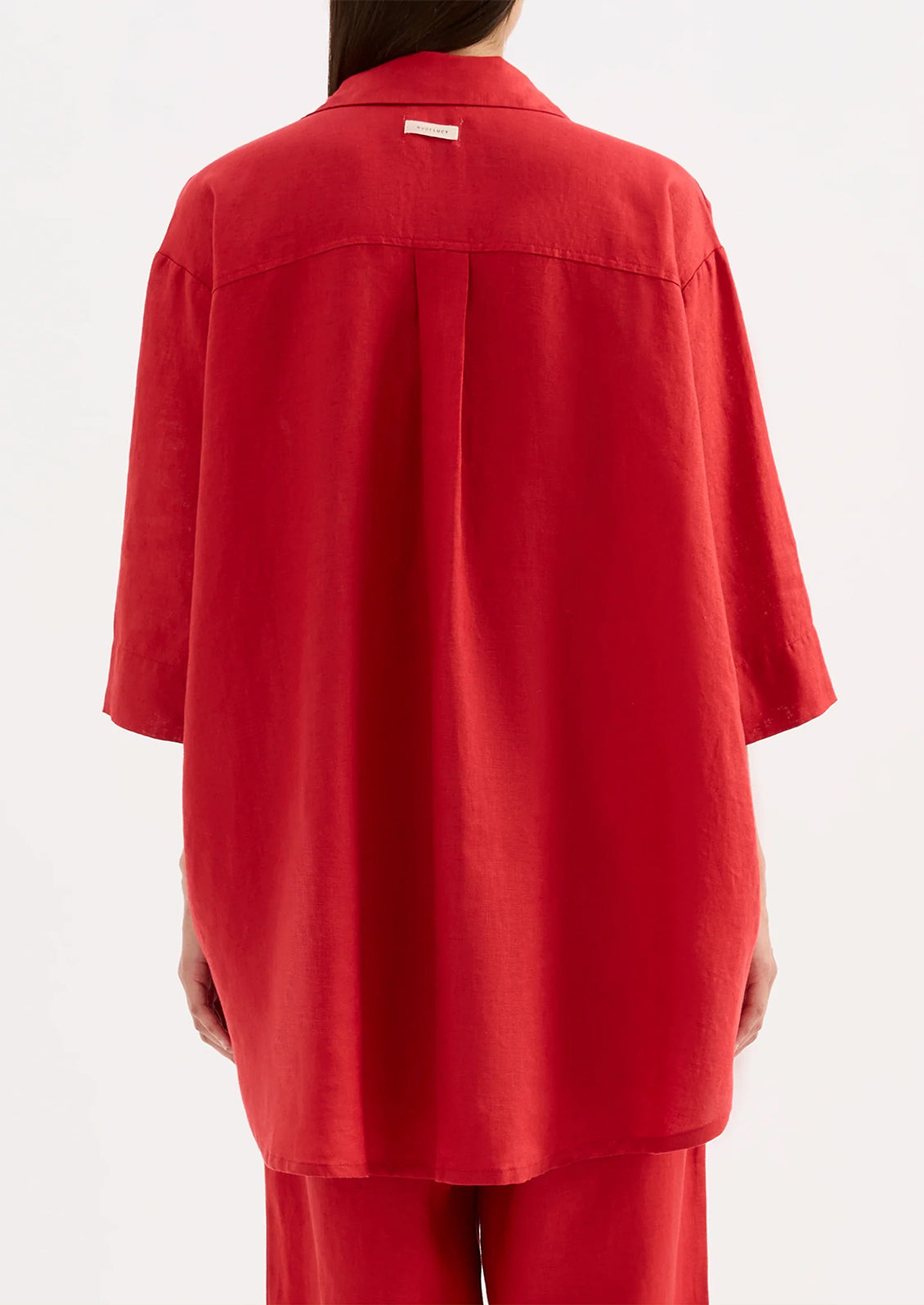 A woman wearing a relaxed red linen shirt.